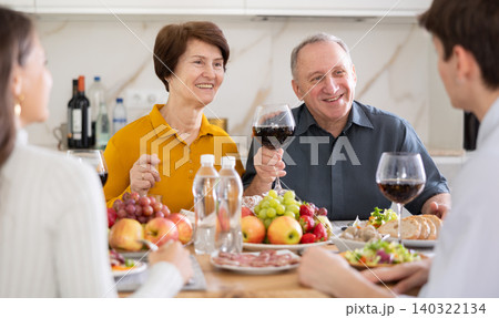 Senior man and woman enjoying family dinner with youth Senior man and woman enjoying family dinner with youth 140322134