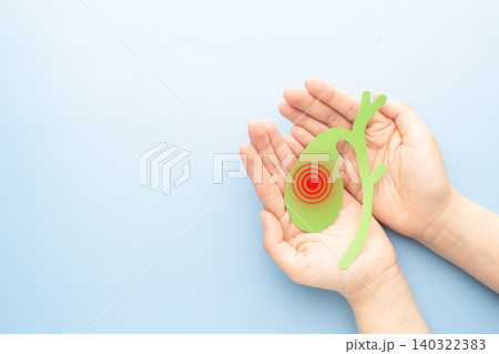 Hands holding gallbladder inflammation made from paper on blue background. Cause of cholecystitis include gallstones, biliary sludge, tumors and sepsis. Hands holding gallbladder inflammation made from paper on blue background. Cause of cholecystitis include gallstones, biliary sludge, tumors and sepsis. 140322383