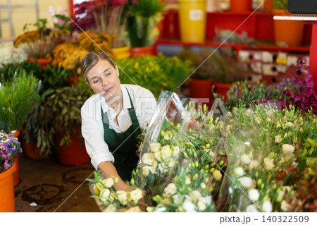 Florist creates bouquet of roses in flower shop Florist creates bouquet of roses in flower shop 140322509