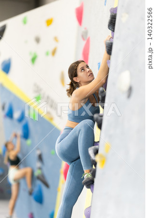 Girl climbs artificial wall bouldering, working out in gym Girl climbs artificial wall bouldering, working out in gym 140322566