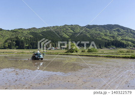 広大な水田と山を背景にした田植え機の風景 広大な水田と山を背景にした田植え機の風景 140322579