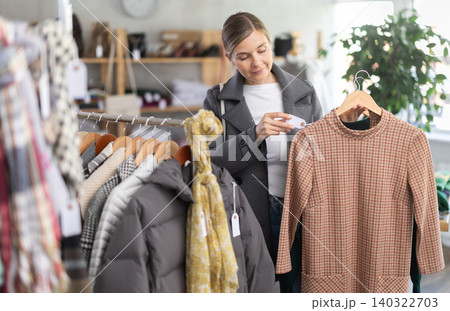 European woman near showcase pick out and buying warm dress European woman near showcase pick out and buying warm dress 140322703