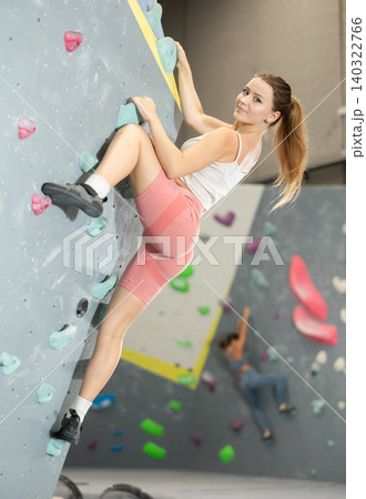 Girl climbs artificial wall bouldering, working out in gym 140322766