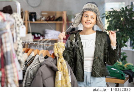 Asian woman is fitting on and trying on fur hat in store Asian woman is fitting on and trying on fur hat in store 140322889