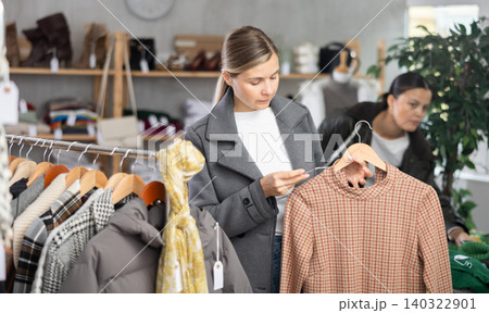 Adult woman chooses warm dress in clothing store Adult woman chooses warm dress in clothing store 140322901