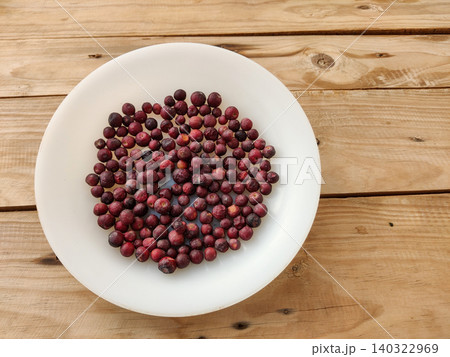 Fresh phalsa berries on white plate over rustic wooden table Fresh phalsa berries on white plate over rustic wooden table 140322969
