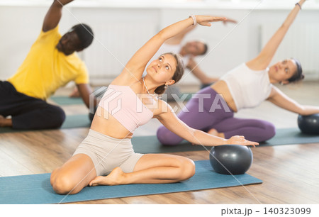 Girl performing Mermaid Stretch with Ball in group Pilates class Girl performing Mermaid Stretch with Ball in group Pilates class 140323099