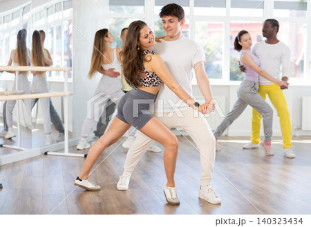 Expressive guy and girl practicing tango during group dance class Expressive guy and girl practicing tango during group dance class 140323434