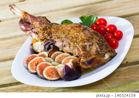 Baked shoulder of lamb served with fig, feta cheese, herbs and cherry tomatoes at plate Baked shoulder of lamb served with fig, feta cheese, herbs and cherry tomatoes at plate 140324159