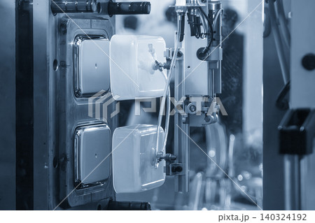 A 2 cavity plastic container box produced by an industrial injection molding machine in a light blue scene. A 2 cavity plastic container box produced by an industrial injection molding machine in a light blue scene. 140324192