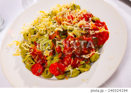 Spinach tortellini served with tomato sauce and greens Spinach tortellini served with tomato sauce and greens 140324194
