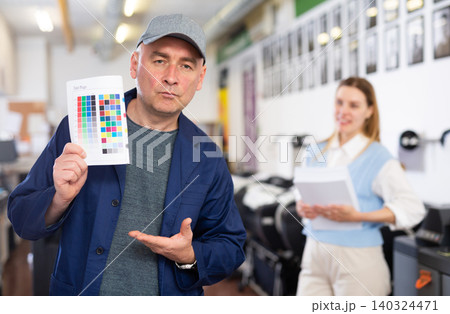 Service engineer demonstrating test page with color palette in his hand Service engineer demonstrating test page with color palette in his hand 140324471