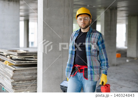Construction worker carrying toolboxes walking on site 140324843