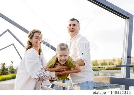 On a Beautiful Sunny Day, Parents Enjoy Lifting Their Child up in the Air, Creating Joyful Memories That Will Last a Lifetime On a Beautiful Sunny Day, Parents Enjoy Lifting Their Child up in the Air, Creating Joyful Memories That Will Last a Lifetime 140325310