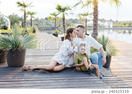A Charming Family Portrait Captured Against the Backdrop of a Serene Wooden Deck Overlooking a Peaceful Lake A Charming Family Portrait Captured Against the Backdrop of a Serene Wooden Deck Overlooking a Peaceful Lake 140325319