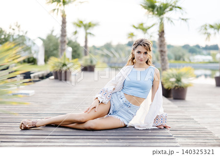 A Woman Relaxing Under a Palm Tree on a Secluded Dock, Surrounded by the Calming Sounds of the Water A Woman Relaxing Under a Palm Tree on a Secluded Dock, Surrounded by the Calming Sounds of the Water 140325321