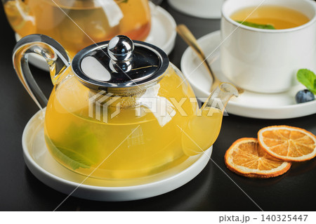 Fruit tea with mango and mint in a glass teapot on the table Fruit tea with mango and mint in a glass teapot on the table 140325447