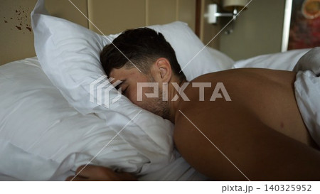 Close up of exhausted young man fall face first into soft pillow on bed in modern hotel room or home interior. Tired guy relax after long day showing fatigue, comfort, rest and cozy indoor lifestyle Close up of exhausted young man fall face first into soft pillow on bed in modern hotel room or home interior. Tired guy relax after long day showing fatigue, comfort, rest and cozy indoor lifestyle 140325952