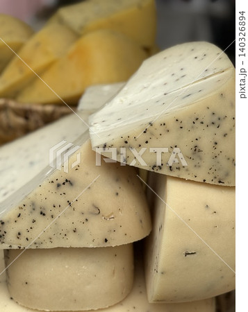 Slices of artisanal truffle cheese with visible specks, showcasing texture and gourmet appeal Slices of artisanal truffle cheese with visible specks, showcasing texture and gourmet appeal 140326894