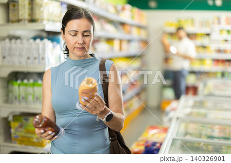 Middle-aged woman choosing vegetable oil in supermarket Middle-aged woman choosing vegetable oil in supermarket 140326901