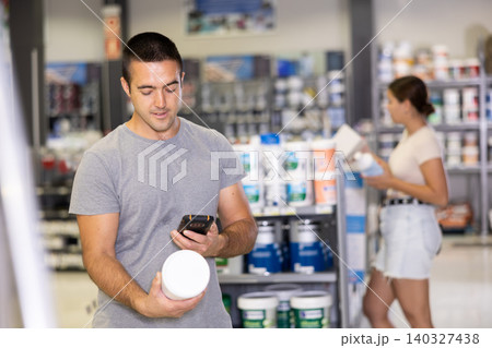 Male shopper scanning a QR code using a mobile phone in hardware store Male shopper scanning a QR code using a mobile phone in hardware store 140327438