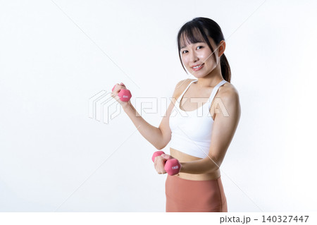 ダンベルを持ち上げ体を鍛える女性 ダンベルカール 筋トレ女子 斜め ダンベルを持ち上げ体を鍛える女性 ダンベルカール 筋トレ女子 斜め 140327447