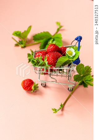 Fresh berry shopping concept with cart angled right on pastel pink background 140327513