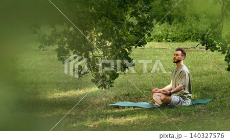 Man Meditating Outdoors Under Tree In Park Man Meditating Outdoors Under Tree In Park 140327576