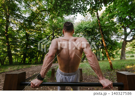 Muscular Athlete Performing Dip Exercise Outdoors 140327586
