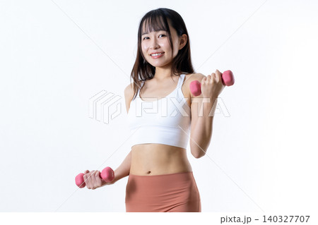 ダンベルを持ち上げ体を鍛える女性 ダンベルカール 筋トレ女子 斜め 中心トリミングアップ ダンベルを持ち上げ体を鍛える女性 ダンベルカール 筋トレ女子 斜め 中心トリミングアップ 140327707