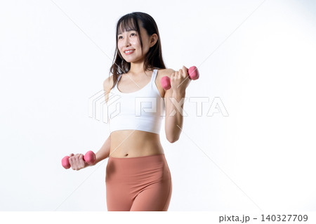 ダンベルを持ち上げ体を鍛える女性 ダンベルカール 筋トレ女子 斜め トリミングアップ ダンベルを持ち上げ体を鍛える女性 ダンベルカール 筋トレ女子 斜め トリミングアップ 140327709