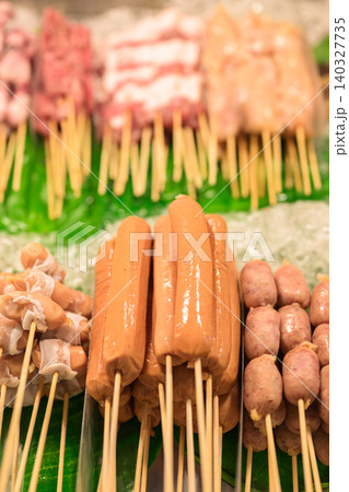 Assorted meat skewers and hot dogs arranged on ice at a market stall Assorted meat skewers and hot dogs arranged on ice at a market stall 140327735