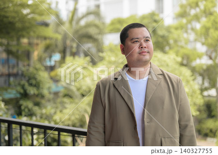 Pensive plus size Isan Thai businessman on balcony horizontal Pensive plus size Isan Thai businessman on balcony horizontal 140327755