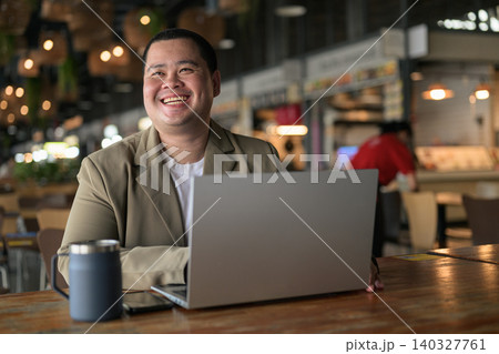 Happy plus size Isan Thai businessman laughing with laptop at cafe Happy plus size Isan Thai businessman laughing with laptop at cafe 140327761