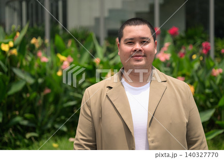Confident plus size Isan Thai businessman in flower garden horizontal 140327770