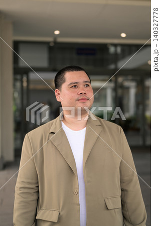 Pensive plus size Isan Thai businessman at office entrance vertical 140327778