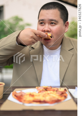 Plus size Isan Thai man eating pizza slice at outdoor restaurant vertical 140327826