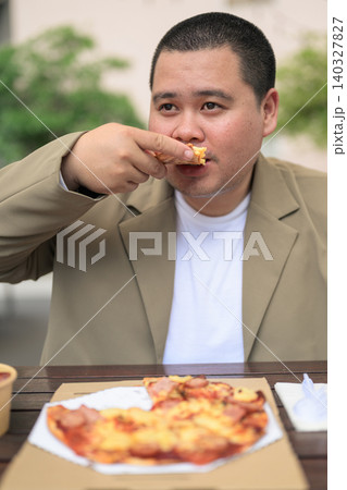 Plus size Isan Thai businessman eating pizza slice outdoors 140327827