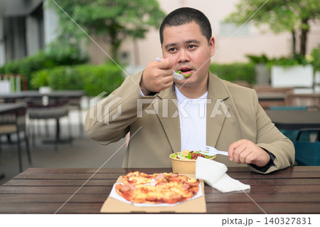 Plus size Isan Thai businessman eating salad at outdoor cafe 140327831