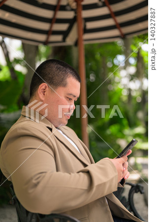 Vertical profile of plus size Isan Thai businessman using phone in garden 140327887