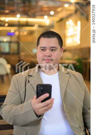 Pensive plus size Isan Thai businessman with phone at restaurant vertical 140327916