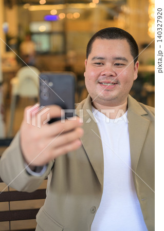Happy plus size Isan Thai businessman taking selfie at restaurant vertical 140327920