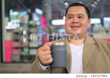 Happy plus size Isan Thai businessman holding mug at night cafe horizontal 140327964