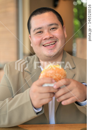 Plus size Isan Thai businessman looking at camera with a burger 140328016