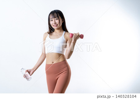 笑顔で体を鍛える女性 水とダンベルを持ちジムで運動イメージ 筋トレ女子 笑顔で体を鍛える女性 水とダンベルを持ちジムで運動イメージ 筋トレ女子 140328104