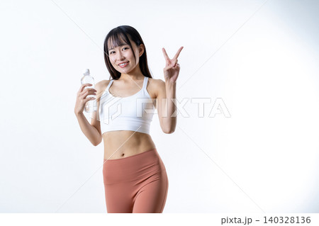 笑顔でピースサインをする体を鍛える女性 水を持ちジムで運動イメージ 筋トレ女子 笑顔でピースサインをする体を鍛える女性 水を持ちジムで運動イメージ 筋トレ女子 140328136