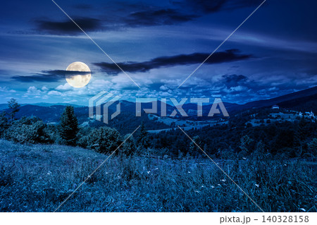 mysterious field on hillside in mountains near village at night. full moon over carpathian mountain landscape in summer. countryside view of alpine fields and rolling hills. cloudy sky mysterious field on hillside in mountains near village at night. full moon over carpathian mountain landscape in summer. countryside view of alpine fields and rolling hills. cloudy sky 140328158