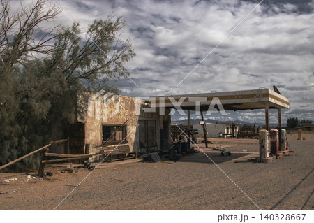 Abandoned desert gas station with vintage pumps under cloudy sky Abandoned desert gas station with vintage pumps under cloudy sky 140328667