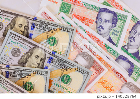 Cuban CUC pesos banknotes with multiple denomination values for finance American hundred dollar bills travel concept Cuban CUC pesos banknotes with multiple denomination values for finance American hundred dollar bills travel concept 140328764