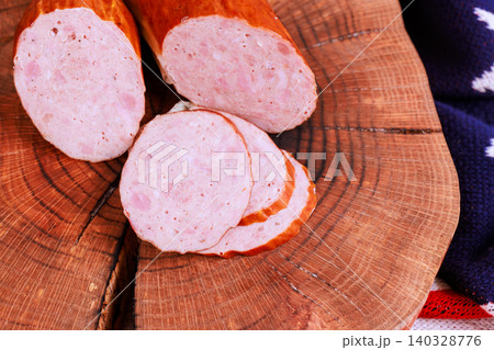 Cured sausage meat is sliced placed on wooden board setting cozy kitchen environment. Cured sausage meat is sliced placed on wooden board setting cozy kitchen environment. 140328776